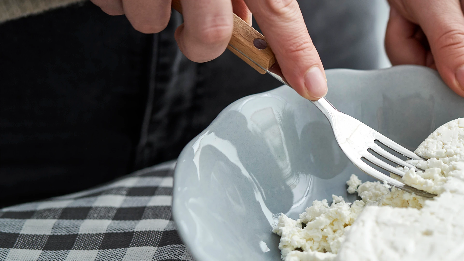 Someone mashing goats cheese with a fork to prepare for spreading