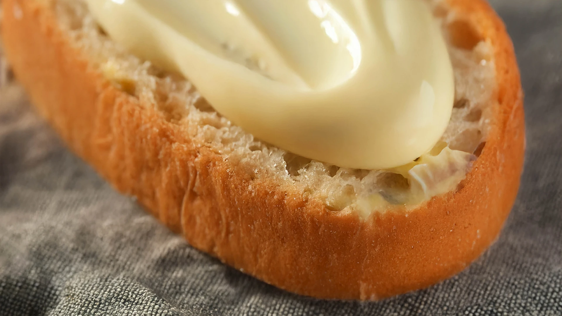 A close up of mayo spread on the bottom half of a sub roll