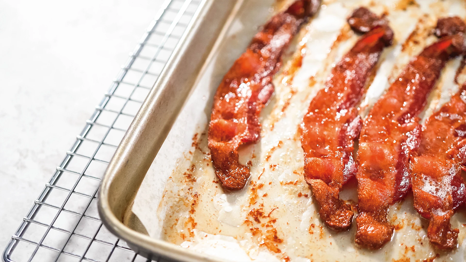 Crispy cooked bacon on a lined baking tray fresh out of the oven 