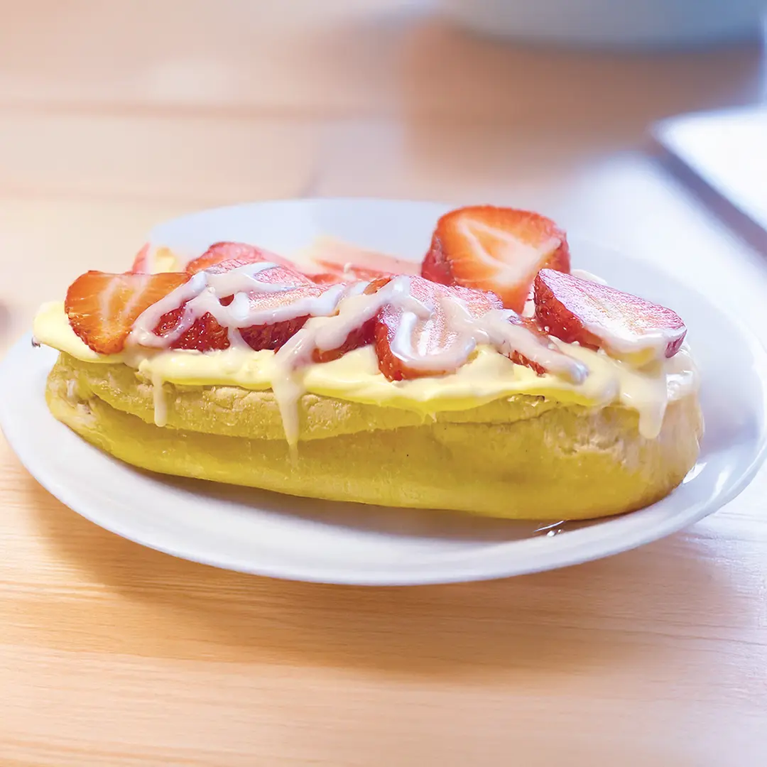 White plate with a Hovis Buttermilk Sub Roll filled with Strawberry and Clotted Cream 