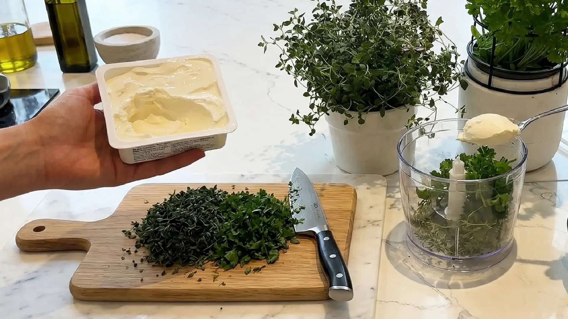 Adding cream cheese to a food processor with fresh herbs and a wooden board of chopped parsley and thyme nearby.