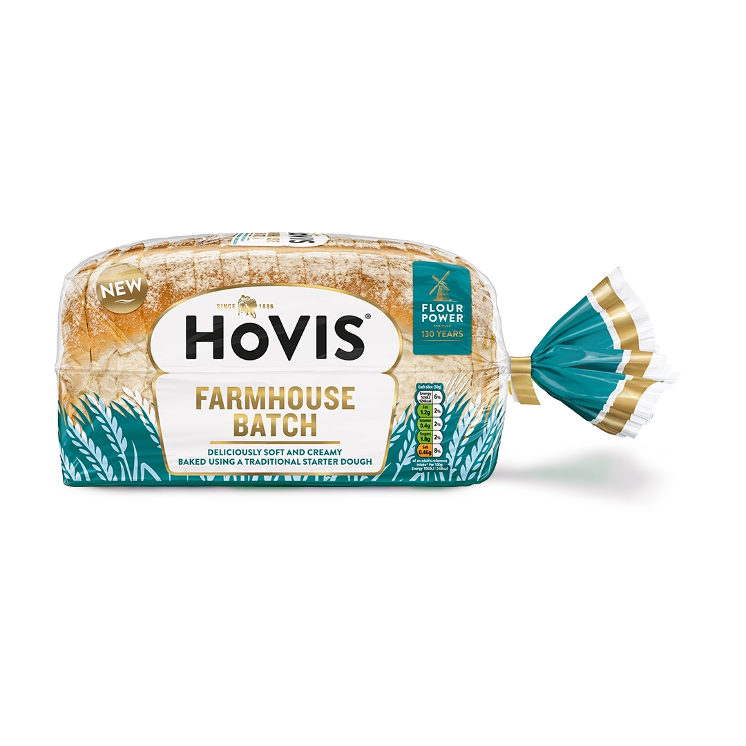 Hovis Farmhouse Batch bread with a subtle shadow under it. The packaging is half transparent and half dark teal, decorated with wheats.