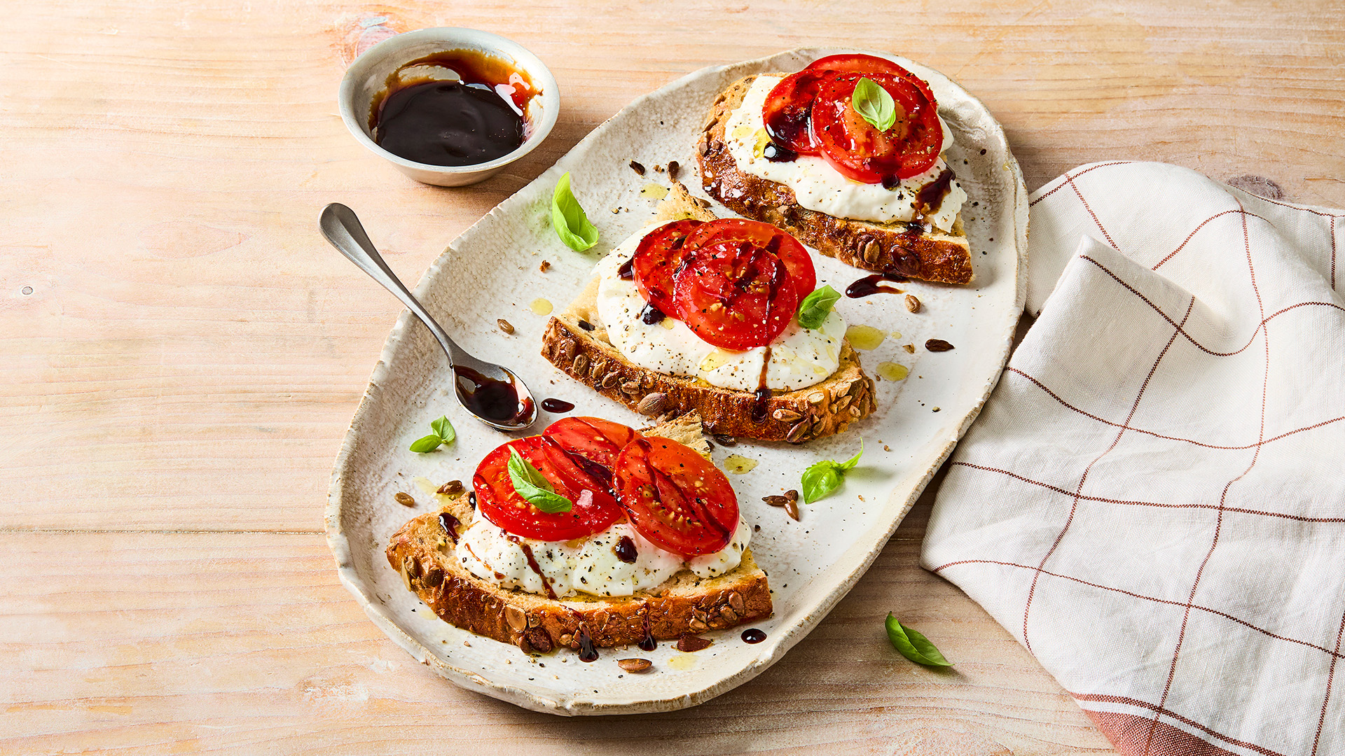 Two slices of a Hovis Seeded Sourdough sandwich filled mozzarella, tomatoes, basil and a drizzle of balsamic vinegar and olive oil.