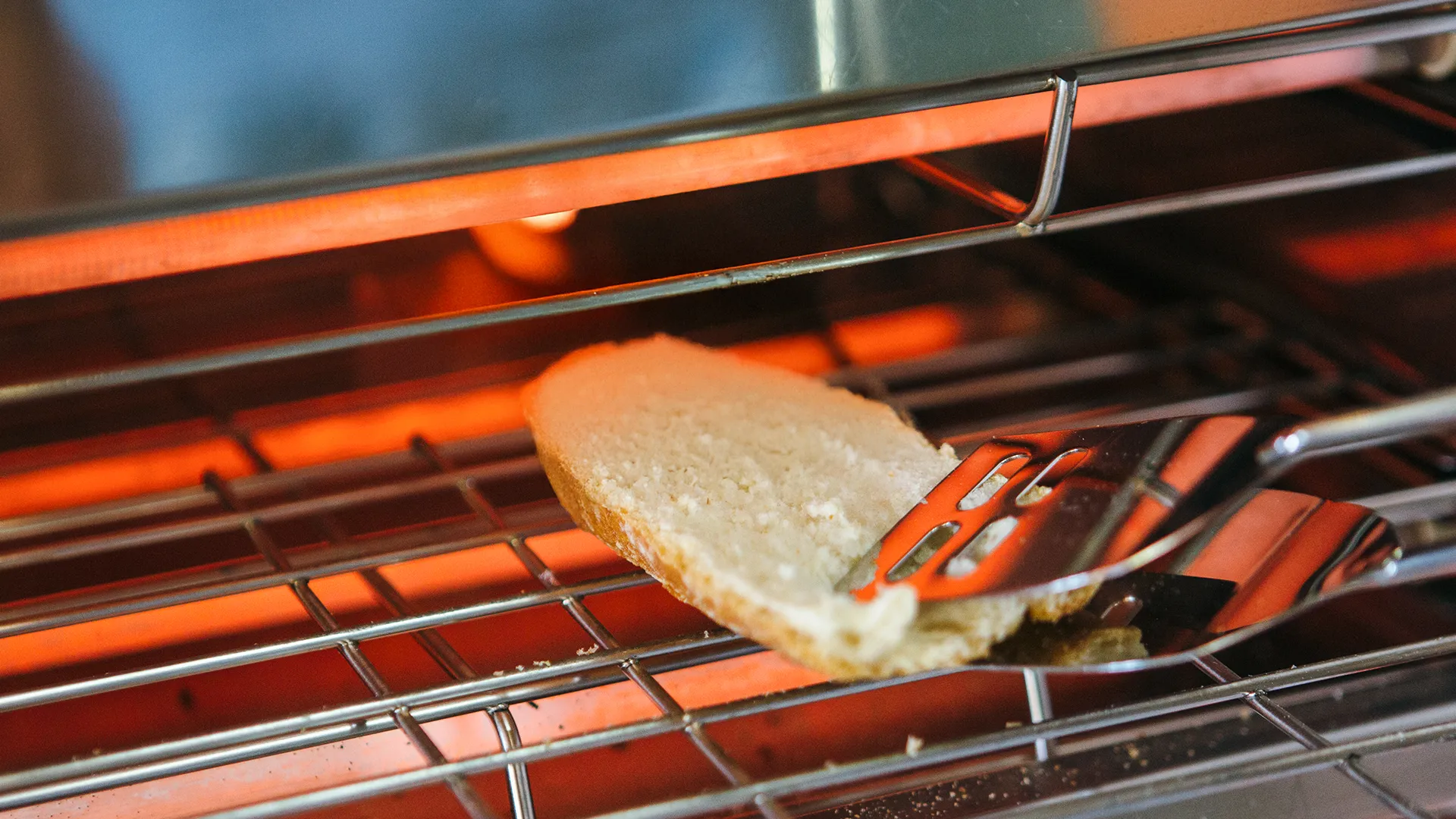 someone is placing a sliced sub roll into a grill with tongs