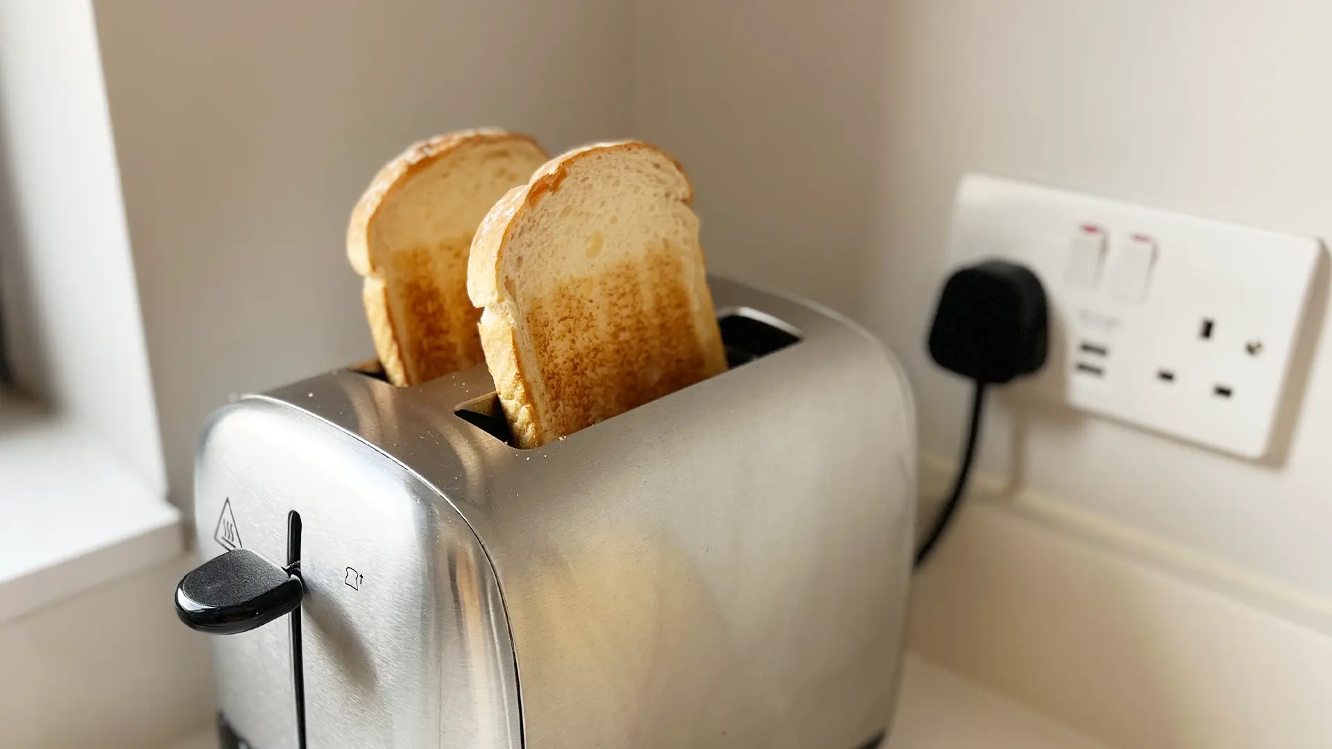 A close-up image of two toasted slices of Hovis® White ‘n’ Fibre in a toaster. 