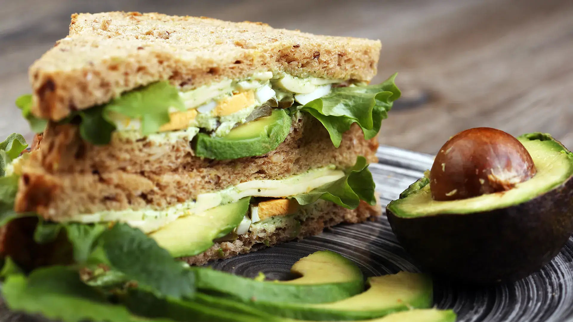 Top-down view of two toasts topped with white creamy cheese, roast cherry tomatoes and basil leaves.