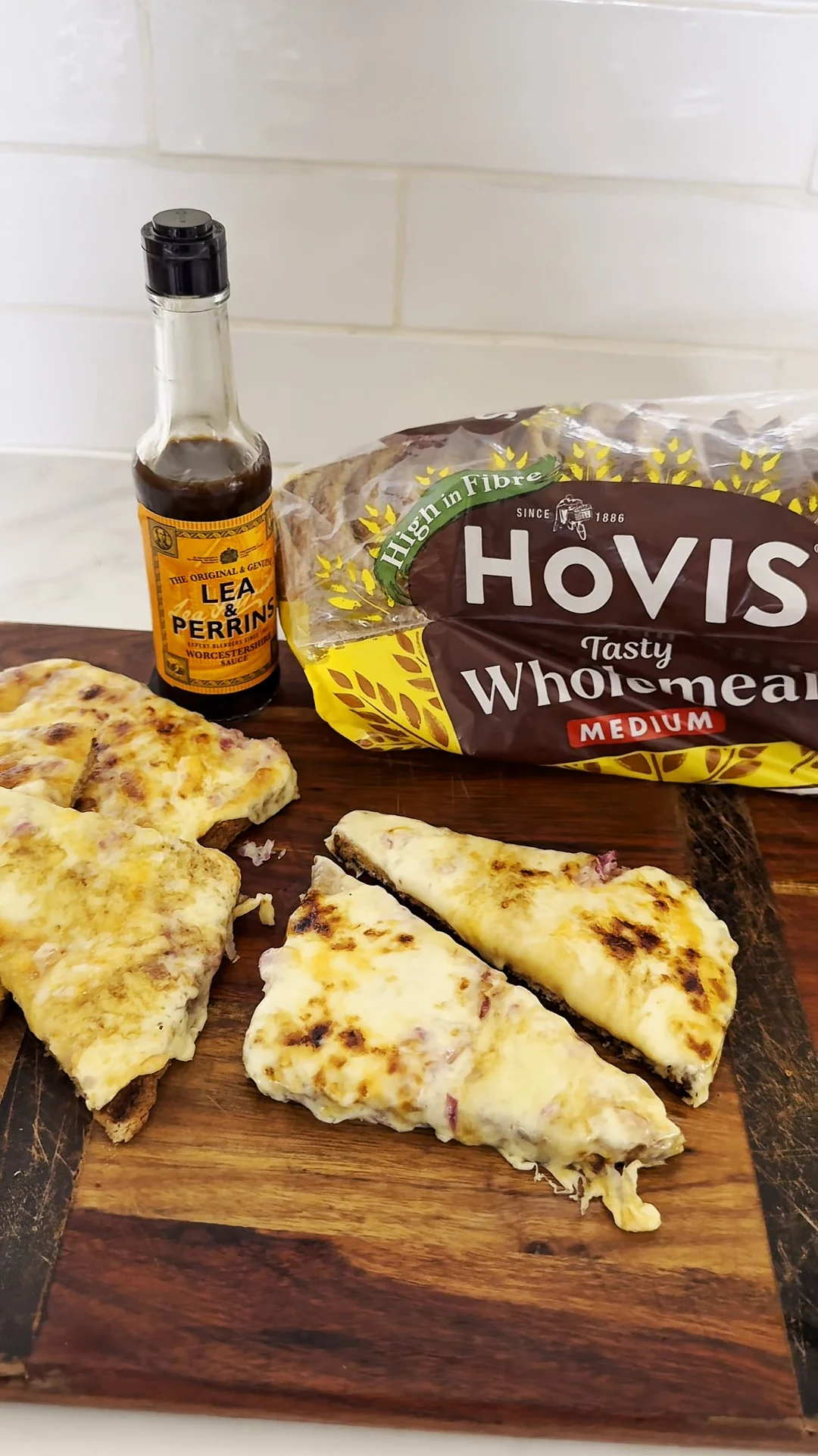 A lea and perrins cheese toastie sits on a wooden board with Hovis Wholemeal sat behind it