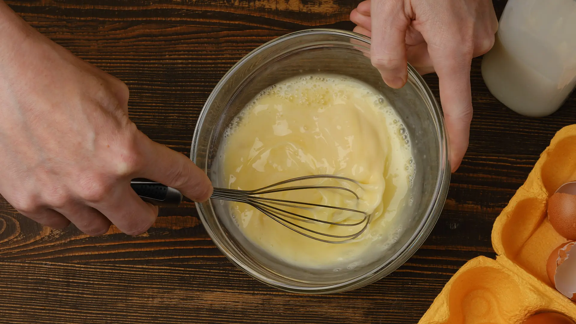 An image of someone whisking together a mixture of milk, eggs, vanilla, cinnamon and salt in a glass bowl.