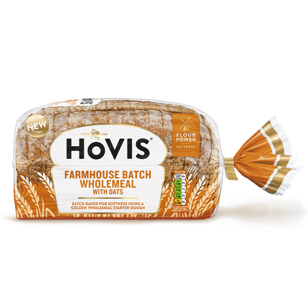 Hovis Farmhouse Batch Wholemeal bread on a white backdrop with a subtle shadow. The packaging is half transparent and orange, decorated with wheats.