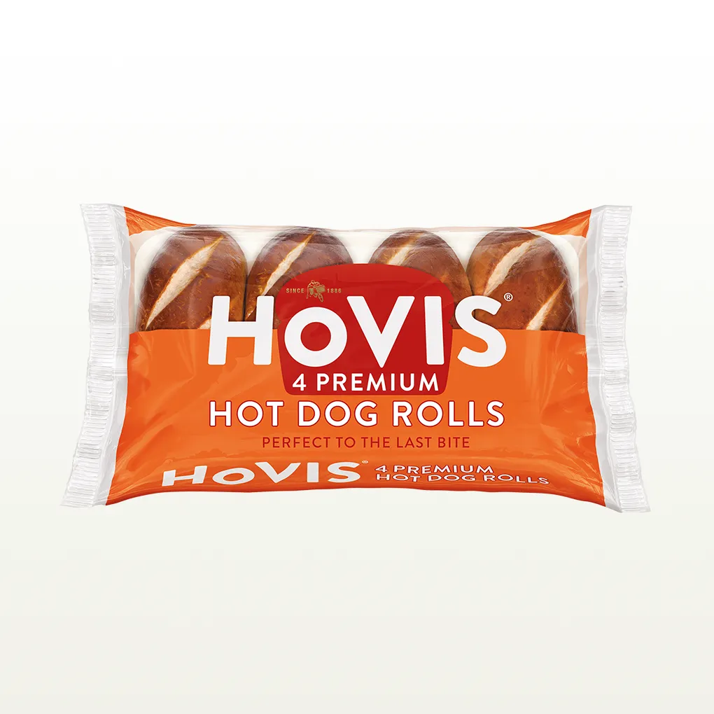 Four Hovis Hot Dog Rolls in a transparent rectangular packaging featuring the Boy on the Bike, a grey stripe, golden wheat, and the Hovis logo on top.