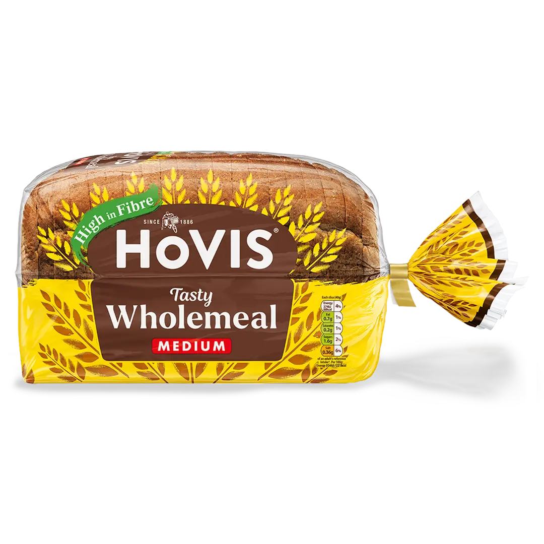 Hovis Tasty Wholemeal Medium Sliced with a subtle shadow under it. The packaging is half transparent and half yellow, decorated with golden wheats.