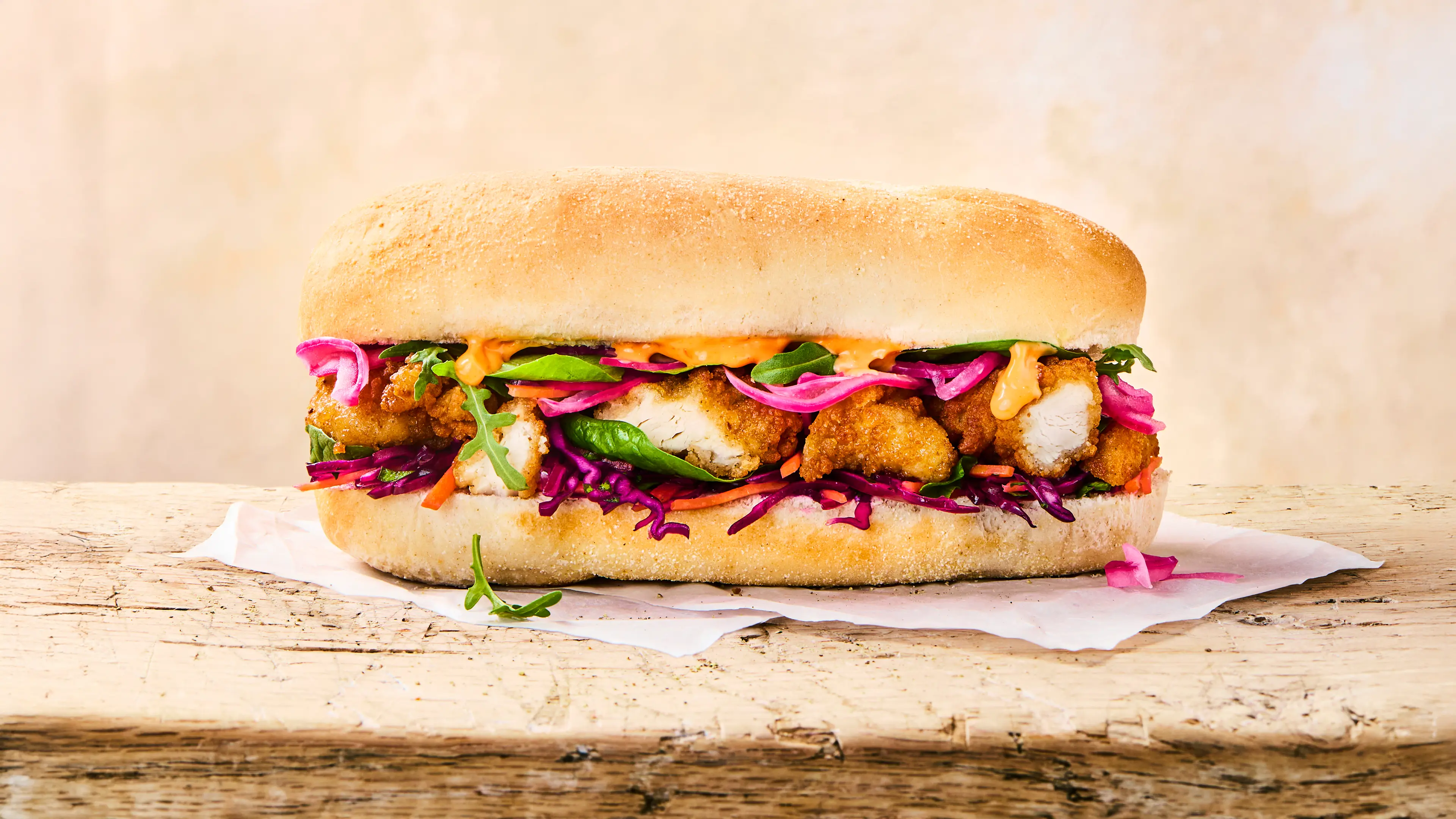 A delicious looking Cajun chicken sub roll sits on a wooden table. 