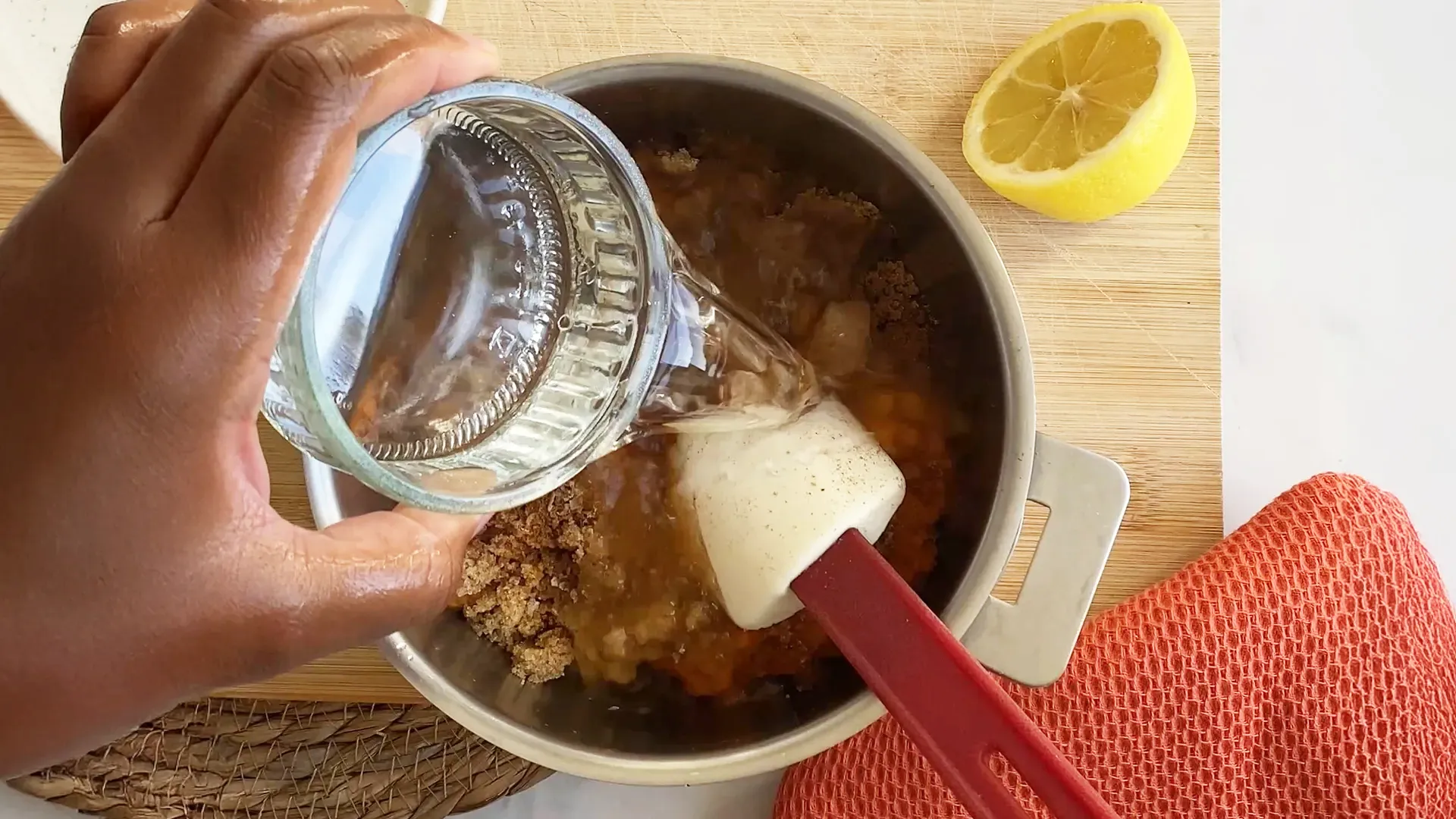 Someone pours the water into the pot with half a lemon nearby ready to be used.