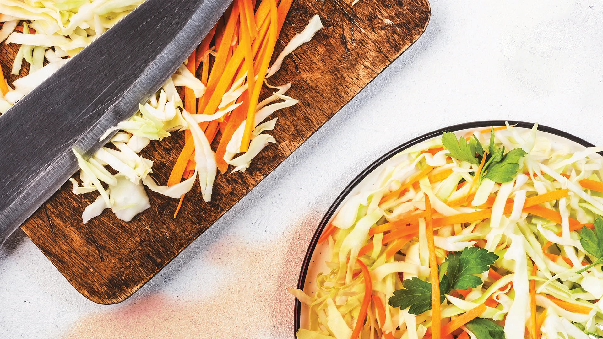 Someone is chopping cabbage for coleslaw on a chopping board. 