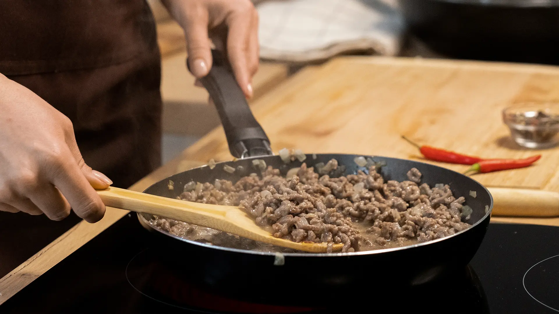 Some one is frying minced pork in a frying pan on a electric stove in a kitchen