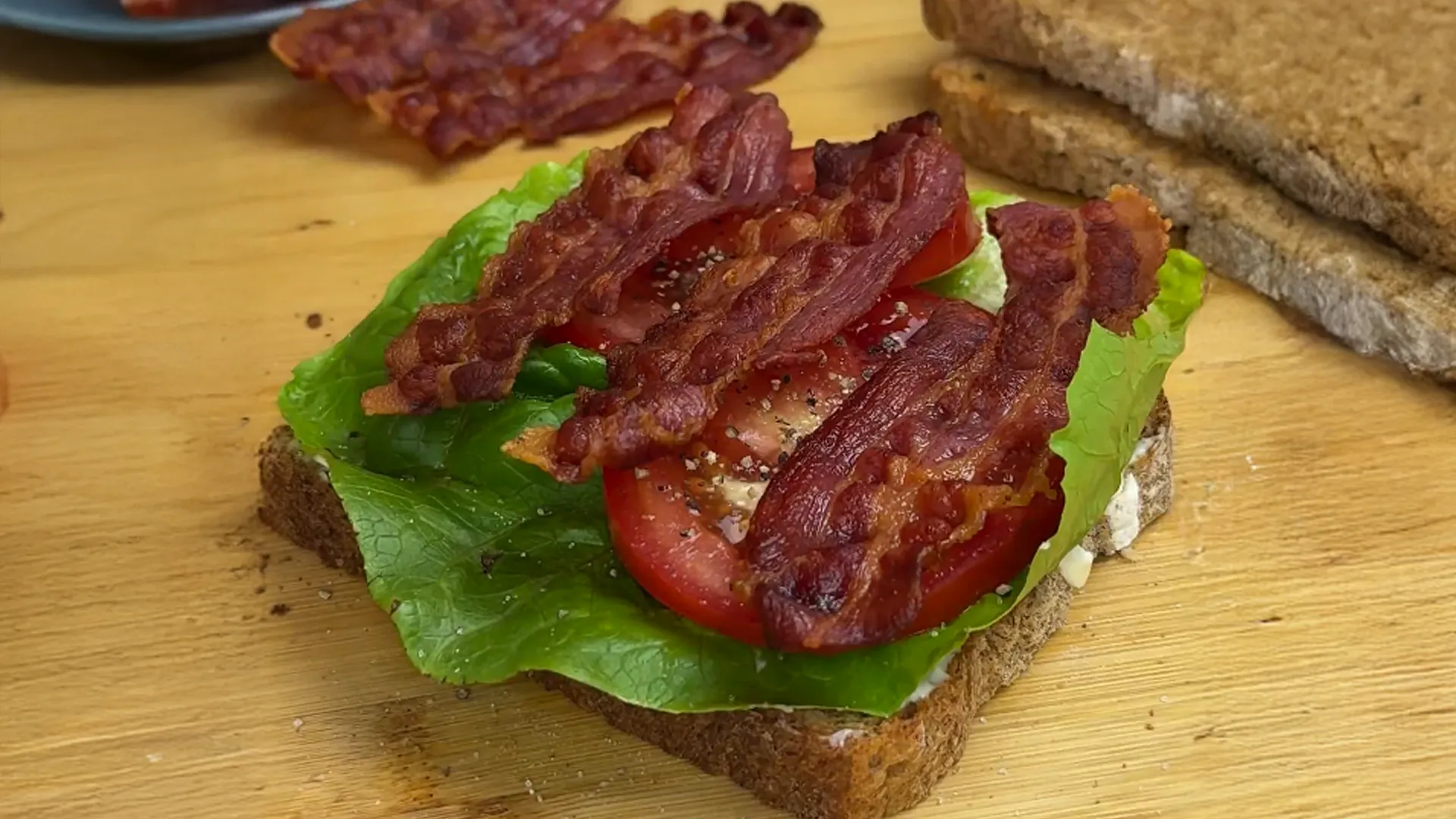 The club sandwich in the making, with lettuce, tomato and bacon layered on top of a toasted slice of Hovis® Farmhouse Batch Wholemeal